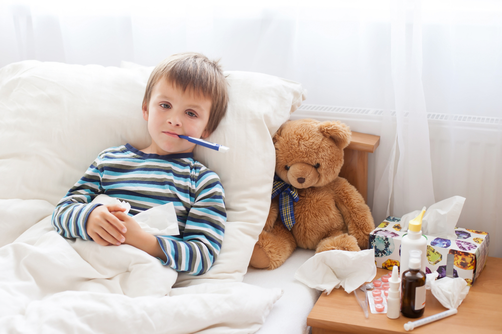 Sick young boy with a fever in bed at home